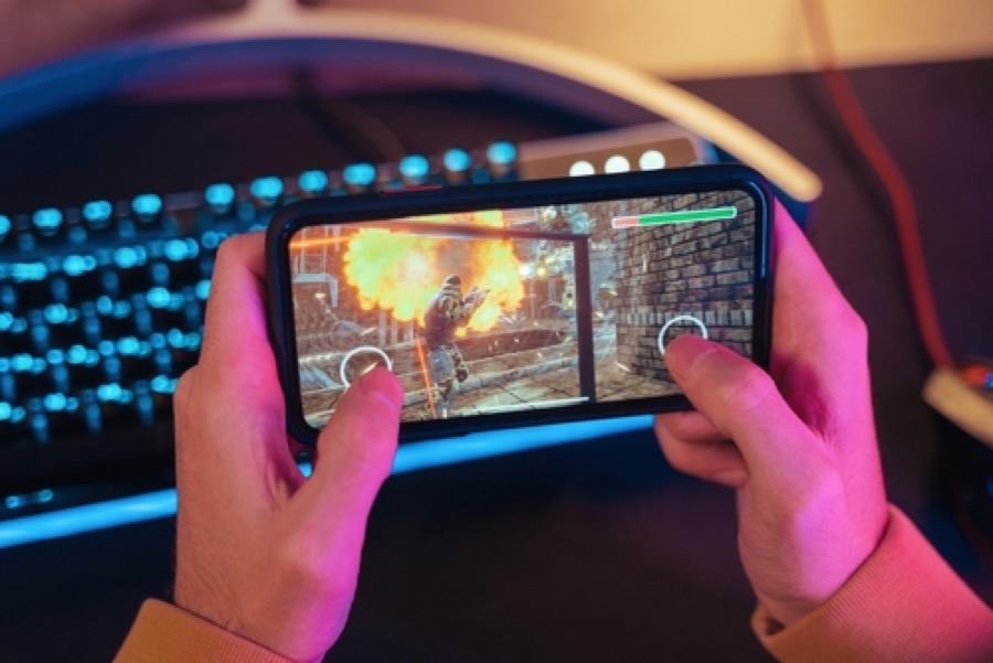 Two hands holding a phone sideways playing an action game